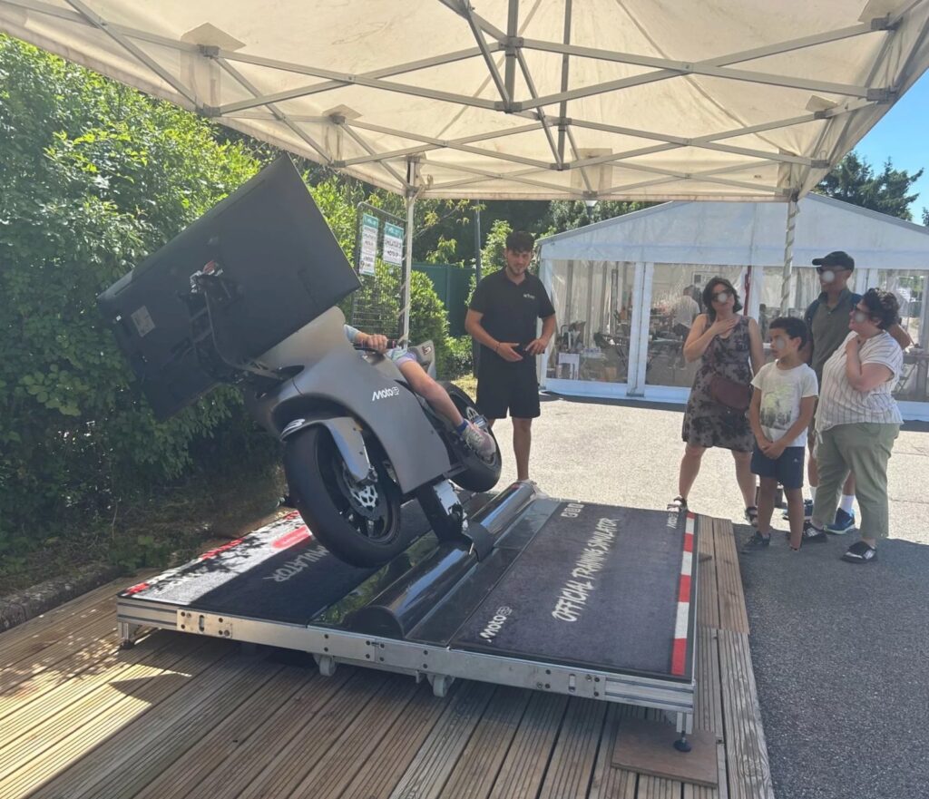 Participante inclinée sur le simulateur de Moto GP à MSL en fête, encadrée par un opérateur Be Event Sensation