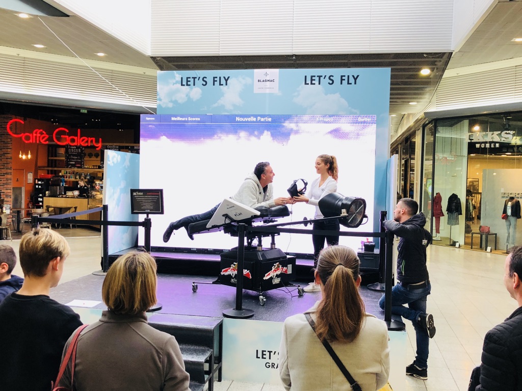 Public rassemblé autour du simulateur de vol en réalité virtuelle au centre commercial de Blagnac
