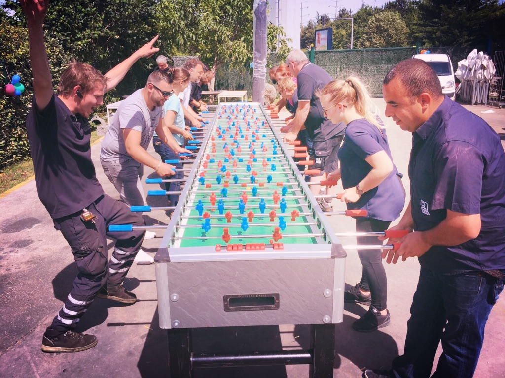 Baby-foot humain géant : une dizaine de participants d'entreprise autour de la table lors d'un team building