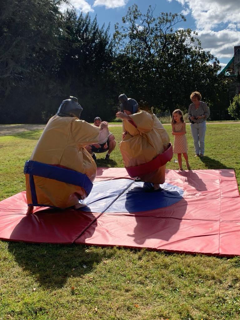 Deux participants en costumes de sumo s'affrontent sur le tapis de réception, en extérieur