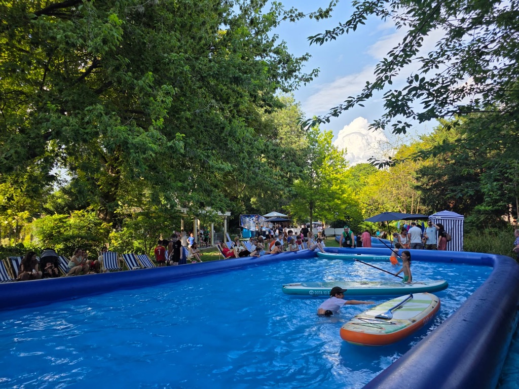 Enfants sur des paddles dans le bassin gonflable du PaddleParc, entouré de transats