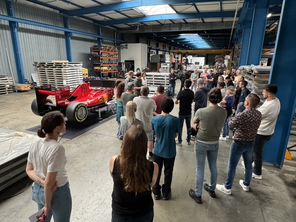 Salariés rassemblés autour du simulateur de Formule 1 installé dans un atelier industriel