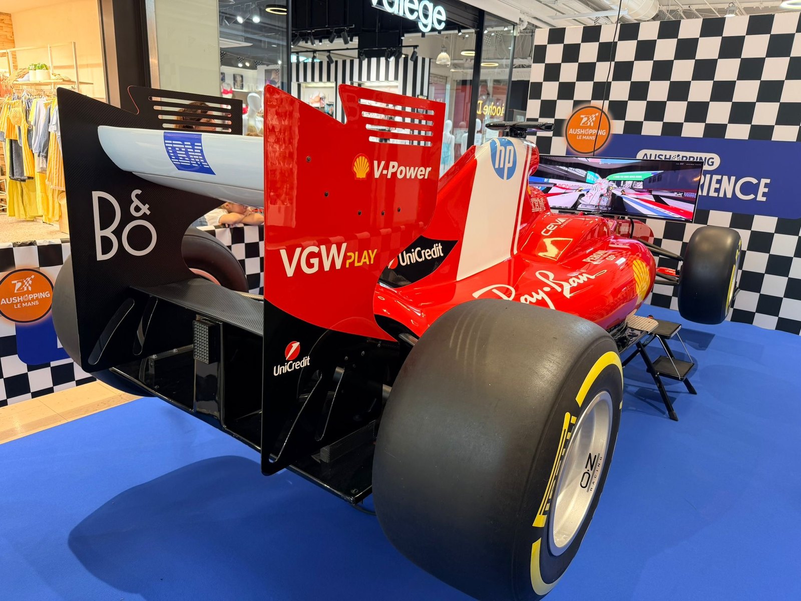 Vue arrière du simulateur de Formule 1 installé dans la galerie d'Aushopping Le Mans, écran de course allumé