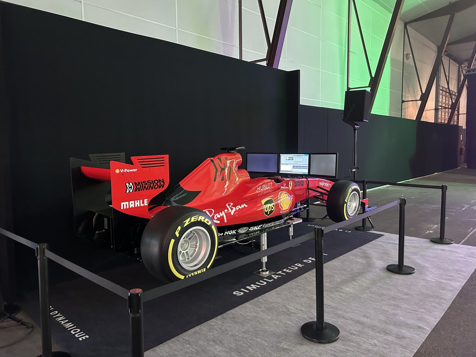 Simulateur de Formule 1 rouge installé sur un salon professionnel, devant un fond noir