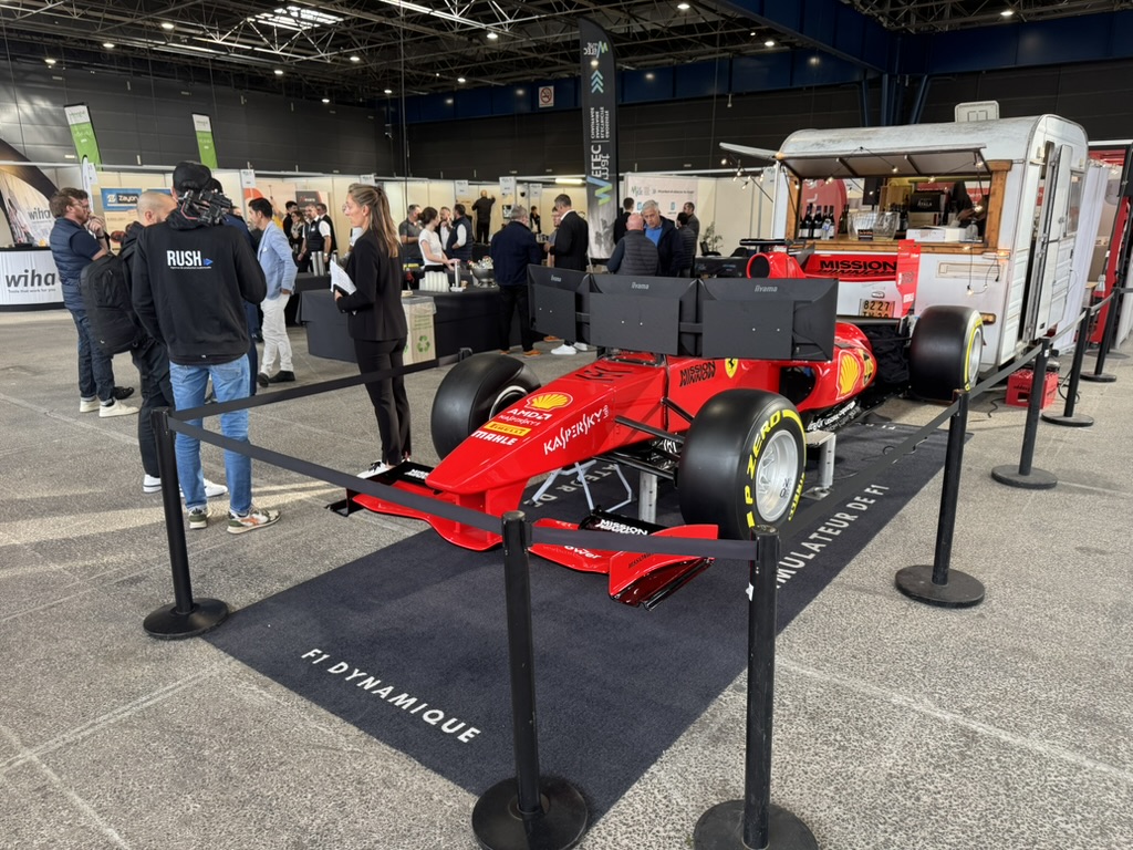 Le simulateur de Formule 1 sur un stand de salon professionnel, avec hôtesse d'accueil