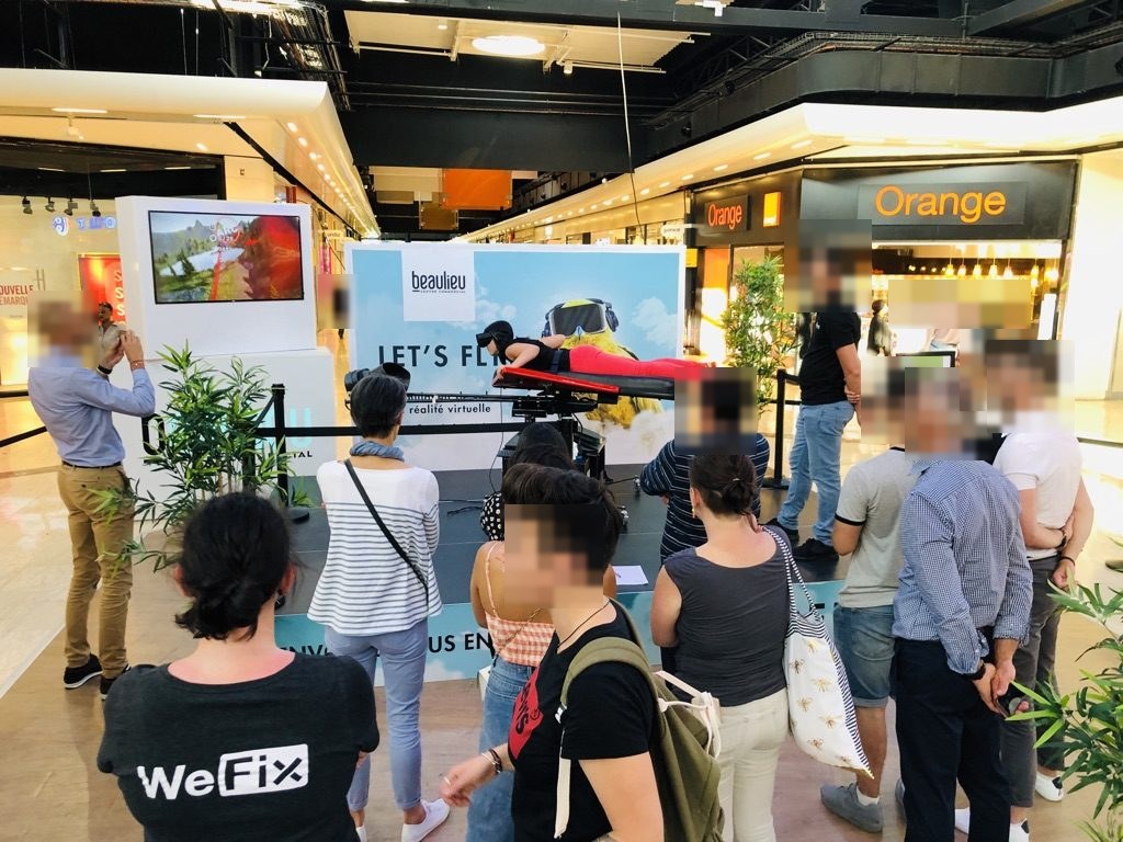 Visiteurs rassemblés autour du simulateur de wingsuit en réalité virtuelle au centre commercial Beaulieu