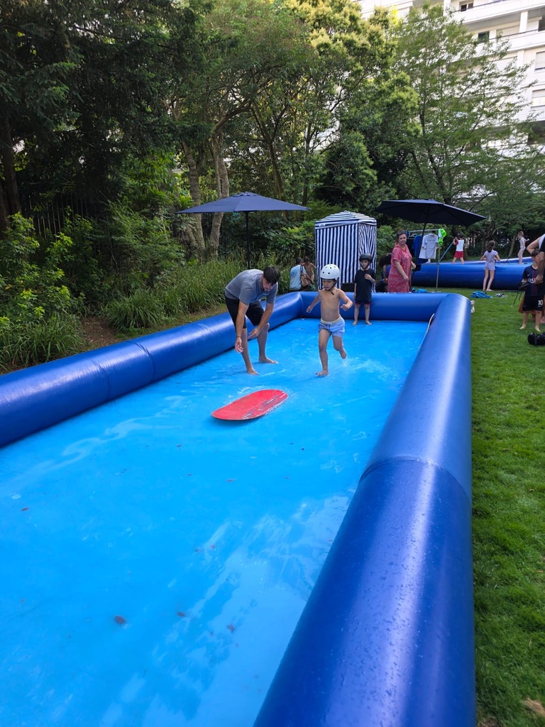 Un moniteur accompagne un enfant sur le SkimParc, bassin gonflable de skimboard